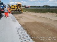 28) 2022-05-08 Prace przy nawierzchni betonowej pasa włączenia z MOP Pepłowo Wschód - widok na pierwszą maszynę Zestawu wykonującą dolną warstwę nawierzchni betonowej